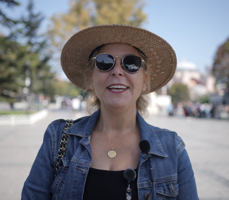a woman wearing a hat and sunglasses posing for the camera