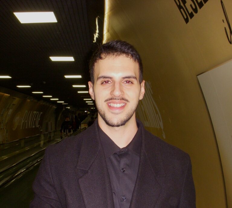 a man wearing a suit and tie smiling at the camera