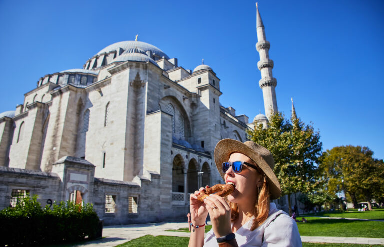 Happy,Attractive,Woman,Tourist,In,Hat,,Eating,Simitci,(a,Round
