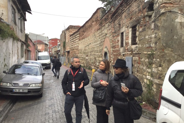 a group of people walking down a street next to a car