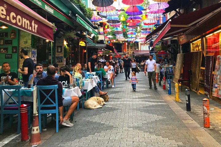 a group of people walking down a sidewalk in front of a store