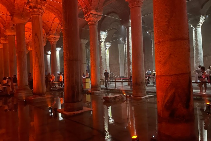 a tall glass building with Basilica Cistern in the background