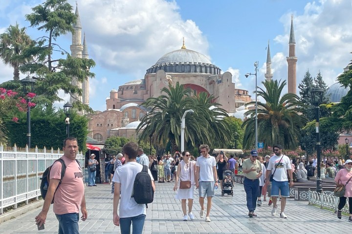 a group of people walking on a sidewalk in front of a crowd