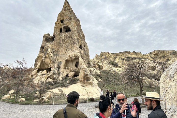 a group of people standing in front of a large rock